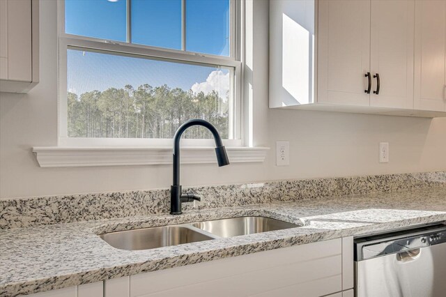 kitchen with kitchen peninsula, appliances with stainless steel finishes, light stone counters, white cabinetry, and hanging light fixtures