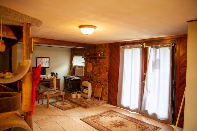 interior space featuring a wood stove, wooden walls, and light tile patterned flooring