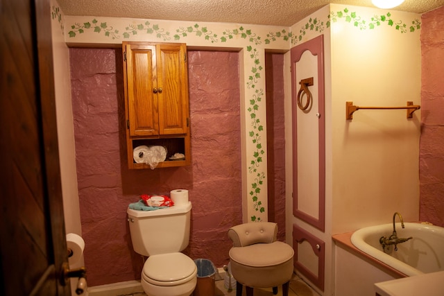 bathroom with a bath, a textured ceiling, and toilet