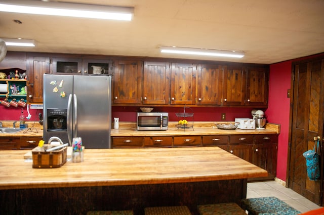 kitchen with light tile patterned flooring, sink, appliances with stainless steel finishes, and wooden counters