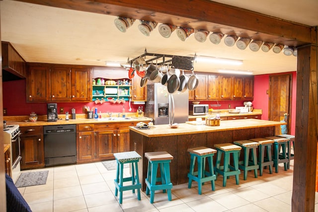 kitchen with black dishwasher, a kitchen breakfast bar, white range, stainless steel refrigerator with ice dispenser, and light tile patterned flooring