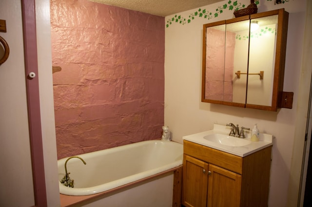 bathroom with vanity, a tub to relax in, and a textured ceiling