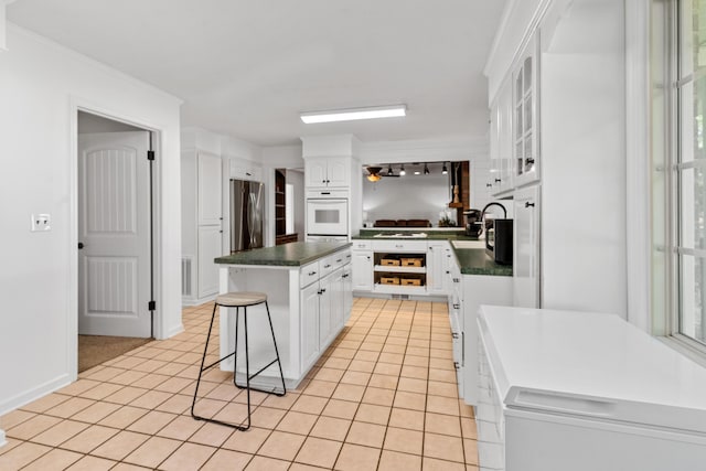 4065 S Goshen Lake Dr, Augusta, GA 30906 - kitchen with a center island, white cabinetry, freestanding refrigerator, dark countertops, and white oven