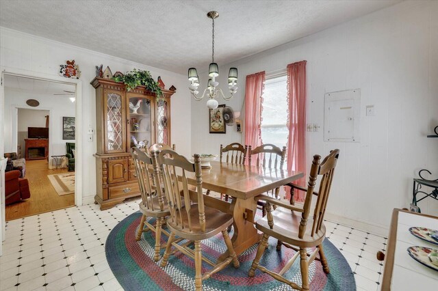 dining room with electric panel, ornamental molding, a textured ceiling, and a notable chandelier