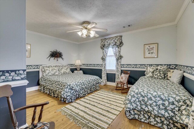 bedroom featuring ceiling fan, crown molding, light hardwood / wood-style floors, and a textured ceiling