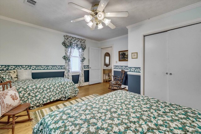 bedroom featuring hardwood / wood-style floors, crown molding, ceiling fan, a textured ceiling, and a closet