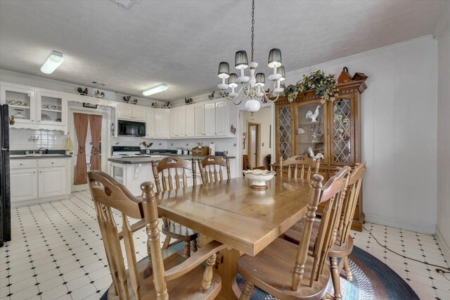 dining space with a textured ceiling, an inviting chandelier, ornamental molding, and sink