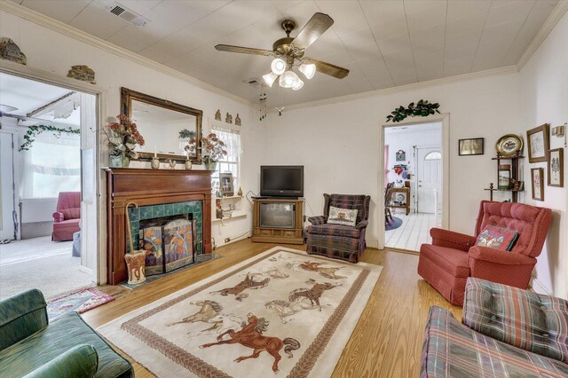 living room with light wood-type flooring, ceiling fan, and ornamental molding