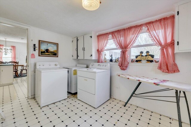 laundry room with washer and clothes dryer, cabinets, and a textured ceiling