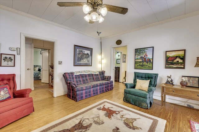 living room featuring light hardwood / wood-style flooring, ceiling fan, and crown molding