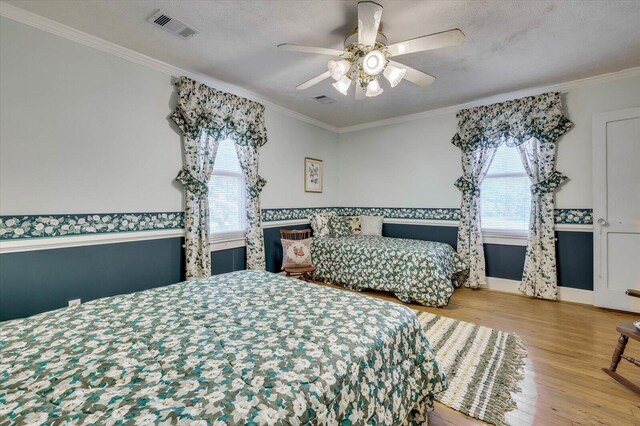 bedroom with ceiling fan, wood-type flooring, ornamental molding, and a textured ceiling