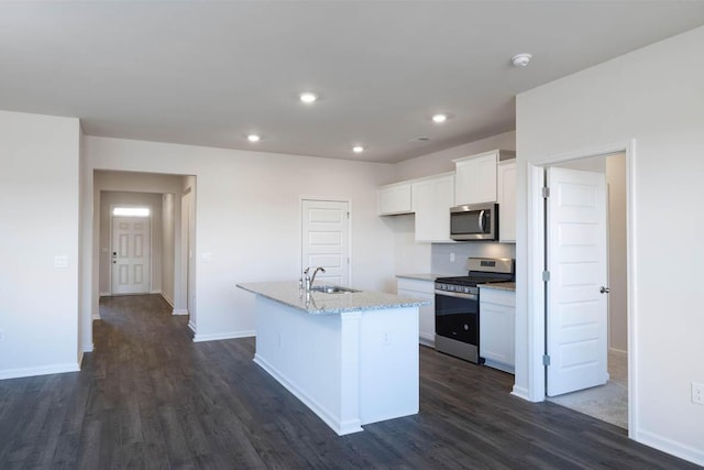 kitchen with dark wood-type flooring, sink, appliances with stainless steel finishes, an island with sink, and white cabinets