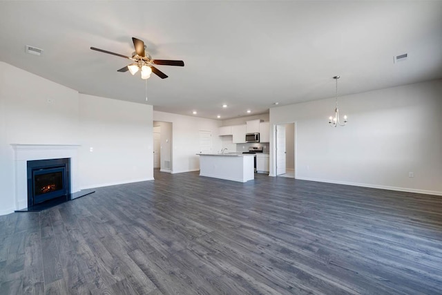 unfurnished living room with sink, dark hardwood / wood-style floors, and ceiling fan with notable chandelier