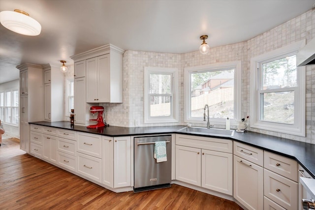 kitchen featuring a sink, dark countertops, light wood finished floors, and dishwasher