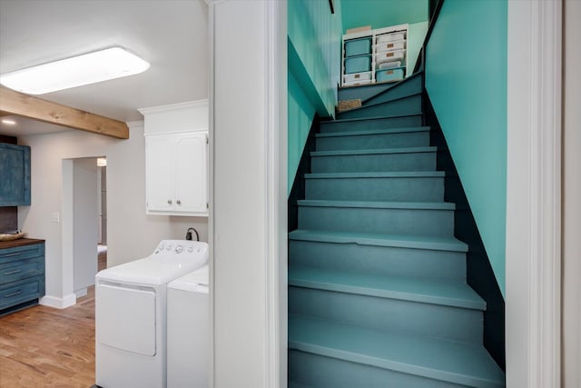 staircase with washing machine and clothes dryer, wood finished floors, beam ceiling, and baseboards