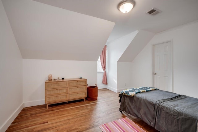 bedroom featuring lofted ceiling, visible vents, and light wood finished floors