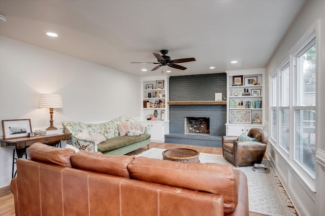 living area featuring recessed lighting, a fireplace, light wood-style flooring, and built in features