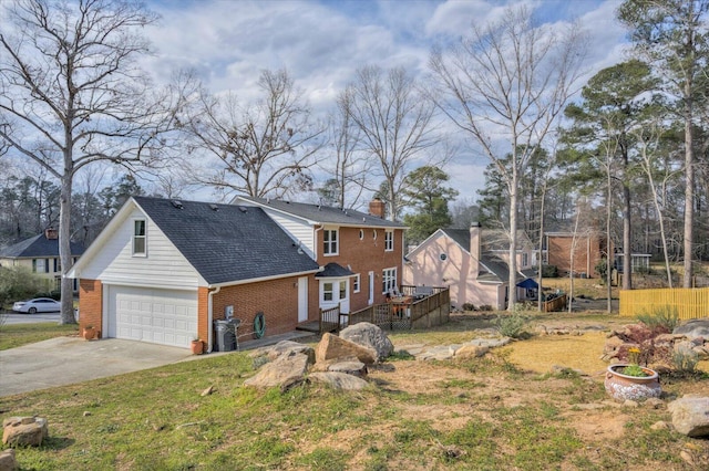 view of front of house with brick siding, a chimney, concrete driveway, a garage, and a wooden deck