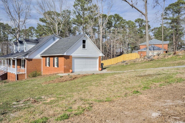 view of home's exterior with a porch, brick siding, fence, a yard, and driveway