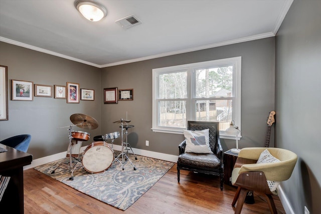 recreation room with baseboards, visible vents, wood finished floors, and ornamental molding