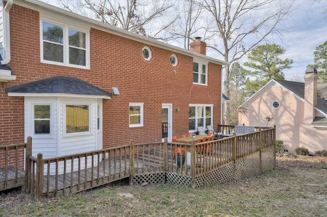 back of house featuring a deck, brick siding, and a chimney