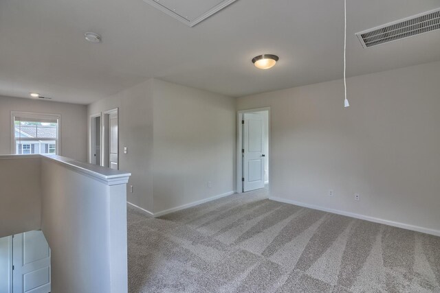 carpeted spare room featuring attic access, visible vents, and baseboards