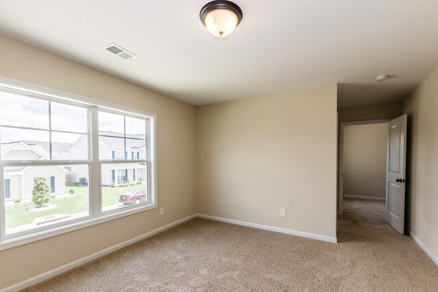 unfurnished room with baseboards, visible vents, and light colored carpet