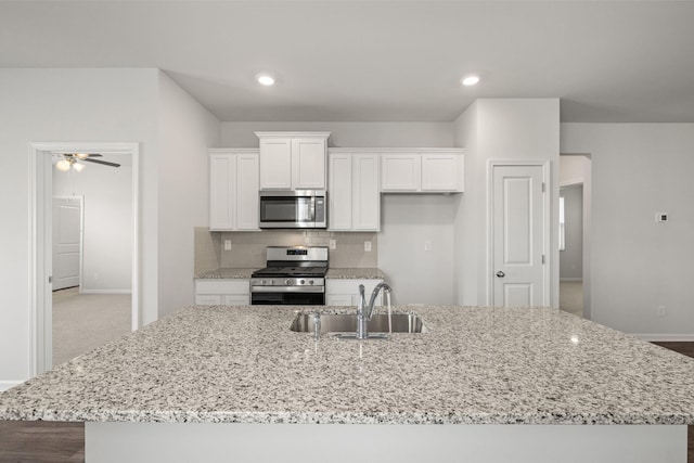 kitchen featuring backsplash, white cabinets, stainless steel appliances, and a sink