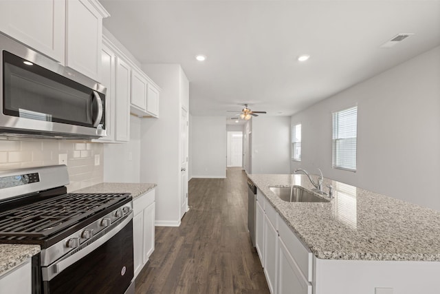 kitchen featuring a ceiling fan, a sink, appliances with stainless steel finishes, white cabinetry, and tasteful backsplash