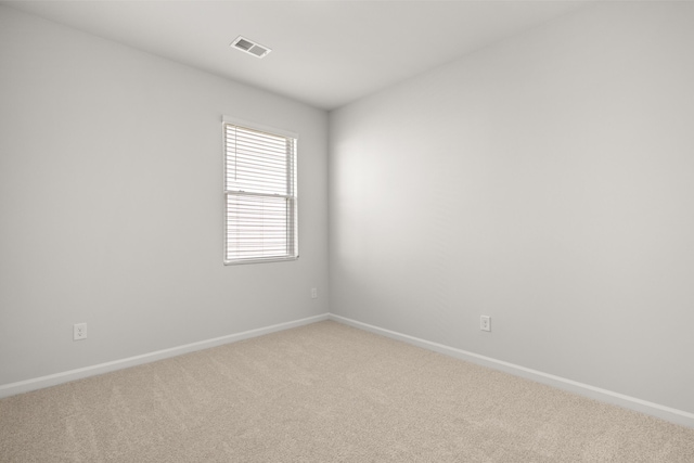 carpeted spare room featuring baseboards and visible vents