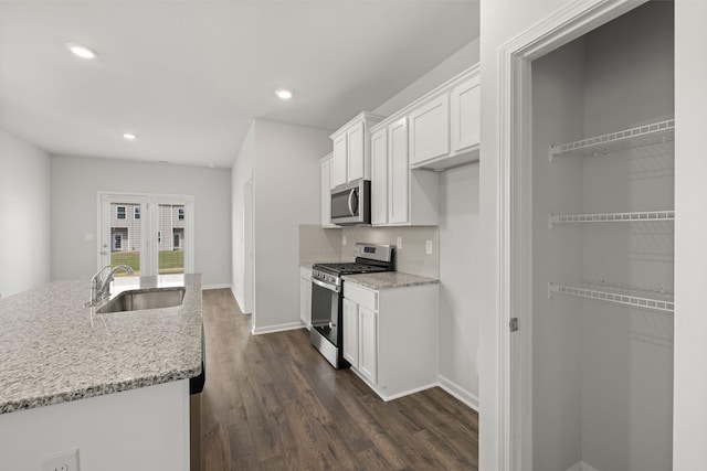 kitchen with dark wood-type flooring, light stone countertops, appliances with stainless steel finishes, white cabinets, and a sink