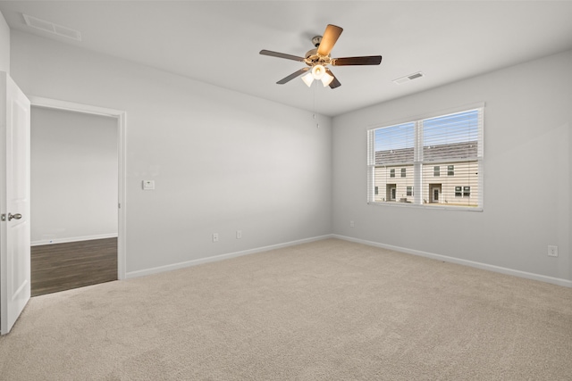 carpeted empty room featuring visible vents, baseboards, and a ceiling fan