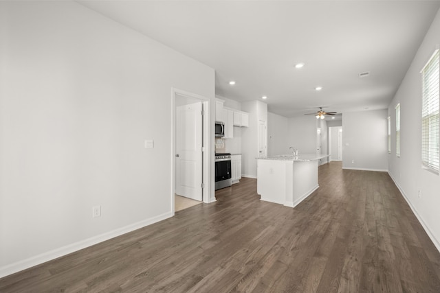 kitchen with a kitchen island with sink, open floor plan, appliances with stainless steel finishes, white cabinets, and dark wood-style flooring