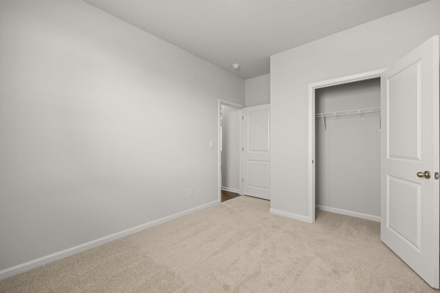 unfurnished bedroom with baseboards, carpet floors, and a closet