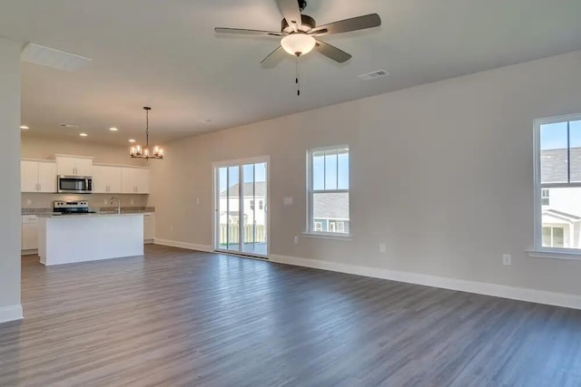 unfurnished living room with hardwood / wood-style floors, ceiling fan with notable chandelier, and sink