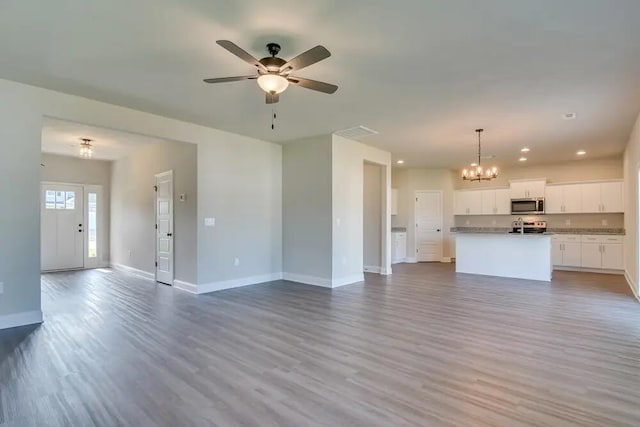 unfurnished living room with ceiling fan with notable chandelier and light hardwood / wood-style flooring