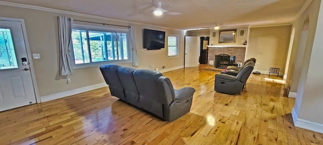 living room featuring a textured ceiling, light hardwood / wood-style flooring, ceiling fan, and crown molding