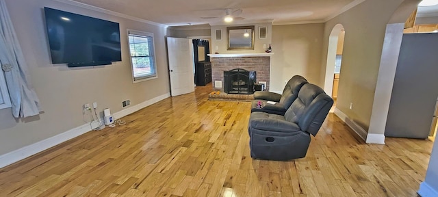 living area with a fireplace, light wood-type flooring, and crown molding