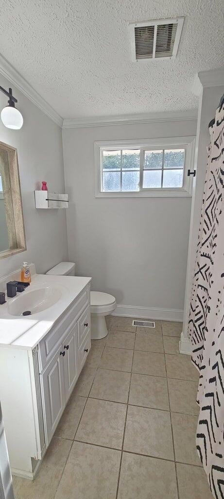 bathroom with tile patterned floors, vanity, toilet, and ornamental molding