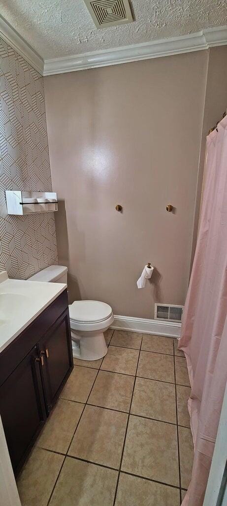 bathroom with tile patterned flooring, crown molding, a textured ceiling, toilet, and vanity