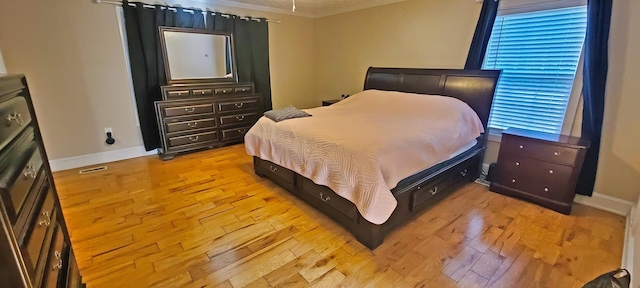 bedroom with light wood-type flooring and crown molding