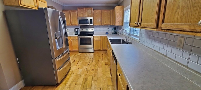 kitchen with sink, decorative backsplash, ornamental molding, light hardwood / wood-style floors, and stainless steel appliances