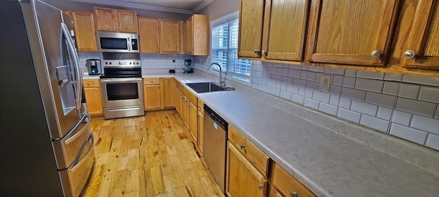 kitchen with sink, decorative backsplash, ornamental molding, light hardwood / wood-style floors, and stainless steel appliances