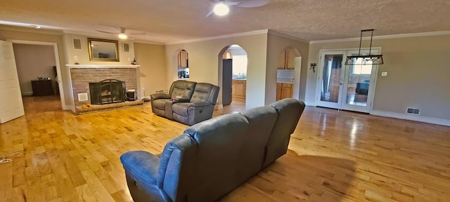 living room with a textured ceiling, light hardwood / wood-style floors, ceiling fan, and ornamental molding