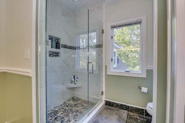 bathroom with a stall shower, toilet, and baseboards