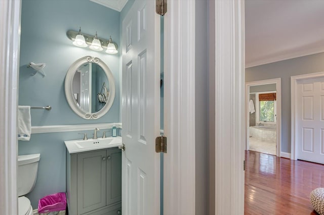 bathroom featuring wood finished floors, vanity, toilet, and crown molding