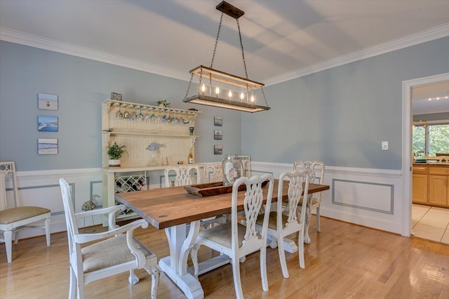 dining room with a wainscoted wall, light wood finished floors, and crown molding