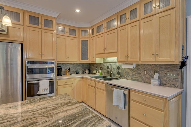 kitchen with stainless steel appliances, a sink, decorative backsplash, light brown cabinetry, and glass insert cabinets