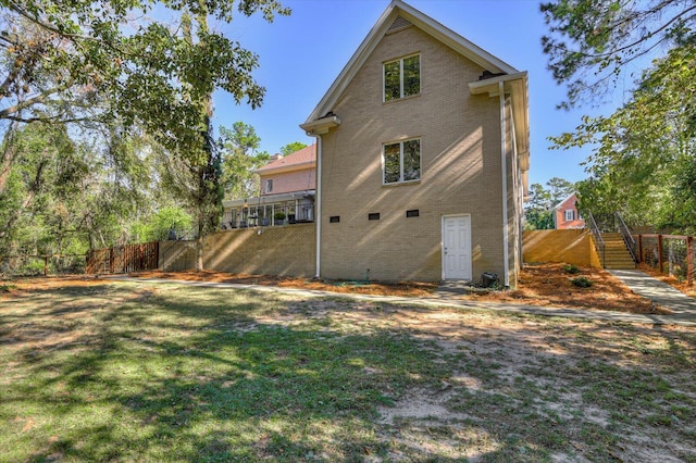 back of property featuring stairs, brick siding, a lawn, and fence