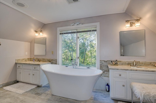 bathroom with lofted ceiling, a freestanding tub, vanity, and tile walls